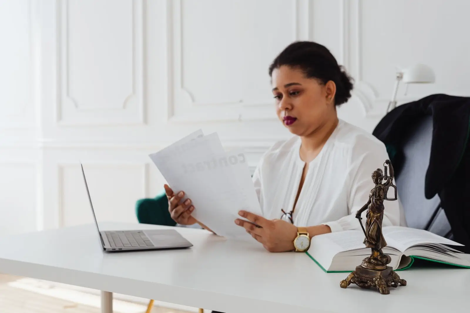 Advogada revisa um contrato impresso ao lado do notebook